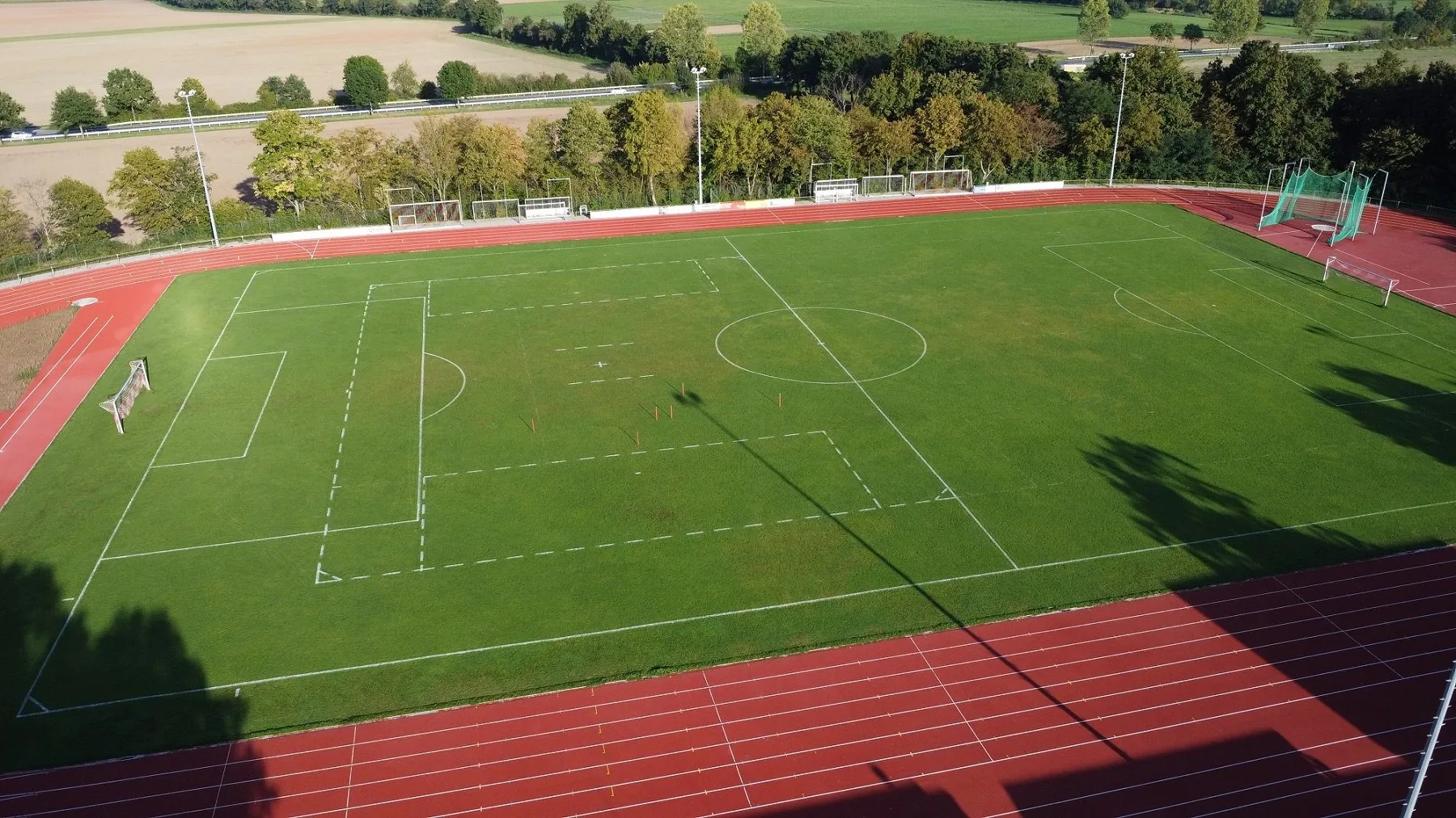 Rasenplatz im Sportzentrum am Zahlwald von oben, umgeben von der Laufbahn und Feldern
